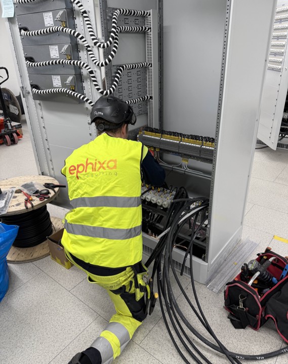 Elektriker i Ephixa-väst som arbetar med inkoppling i ett styrskåp